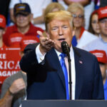 Man speaking at rally with crowd behind him