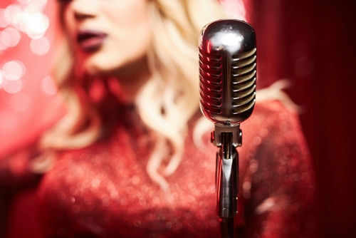 Person singing with vintage microphone in bright setting
