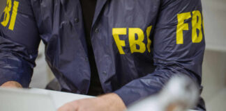Person in FBI jacket typing on laptop