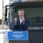 A speaker passionately addressing an audience in front of an electric truck