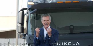 A speaker passionately addressing an audience in front of an electric truck