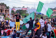 Trump Faces Pressure: Archbishop Demands US Weapons for Nigeria Group of people holding Nigerian flags during demonstration.