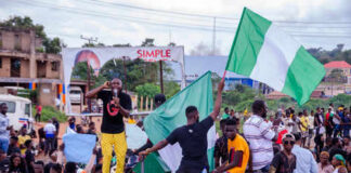 Group of people holding Nigerian flags during demonstration.