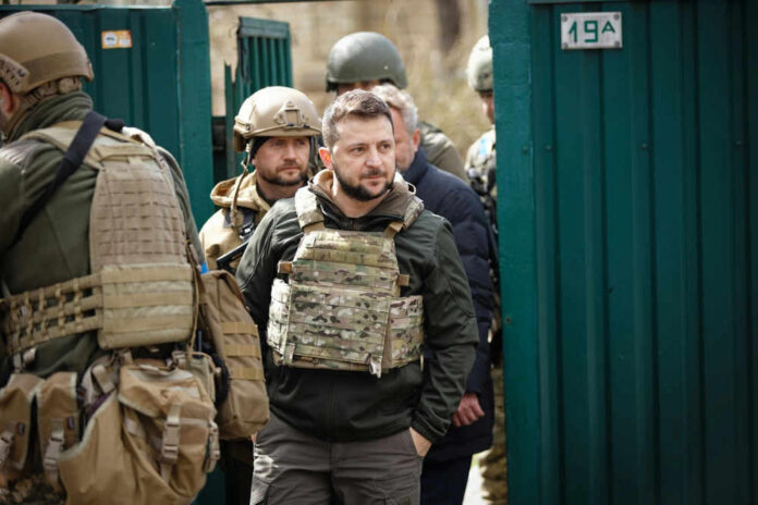 Men in military gear in front of green gate.