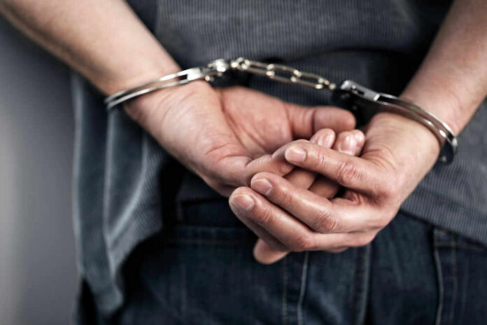 70908647 Person handcuffed with hands behind back.