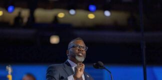 A man speaking at a podium with microphones