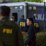 FBI and SWAT team gathered near vehicle.