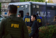 FBI and SWAT team gathered near vehicle.