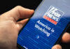 Hand holding smartphone showing Fox News Channel logo.