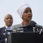Woman speaking at a podium with microphones