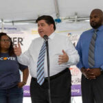 Three people speaking at a promotional event.