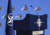 NATO podium with flags and microphones.
