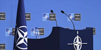 NATO podium with flags and microphones.