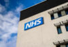 Building with NHS sign and windows against blue sky.