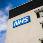 Building with NHS sign and windows against blue sky.