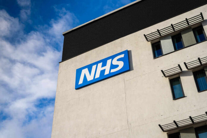 Building with NHS sign and windows against blue sky.