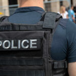 Police officer wearing vest facing crowd outdoors