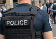 Police officer wearing vest facing crowd outdoors