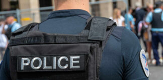 Police officer wearing vest facing crowd outdoors