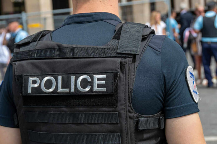 Police officer wearing vest facing crowd outdoors