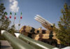 Iran STRIKES Saudi Air Base — U.S. Tankers Hit Military missiles displayed outdoors with Iranian flags in the background