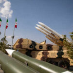 Iran STRIKES Saudi Air Base — U.S. Tankers Hit Military missiles displayed outdoors with Iranian flags in the background