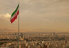 Stunning CIA Plot: Destabilize Iran from Within Iranian flag waving over a city skyline with mountains in the background