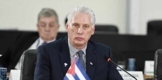 Cuban representative at a political meeting with a flag on the table