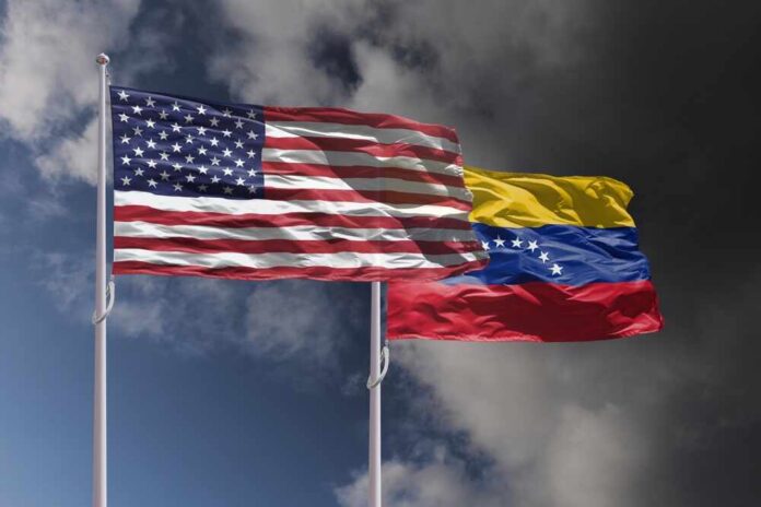 shutterstock_2721741549.jpg Flags of the United States and Venezuela waving against a cloudy sky