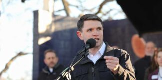 A speaker addressing an audience at an outdoor event with a microphone