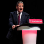 A man in a suit speaking at a podium.