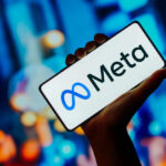 Hand holding phone displaying Meta logo.