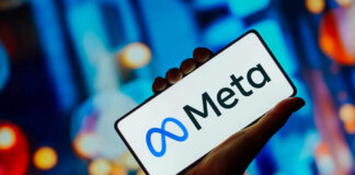 Hand holding phone displaying Meta logo.