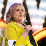 Hillary’s “Brain-Dead” GOP Rant Backfires Spectacularly Person in yellow jacket speaks into microphone.