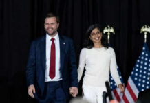 Man and woman holding hands on stage with flags
