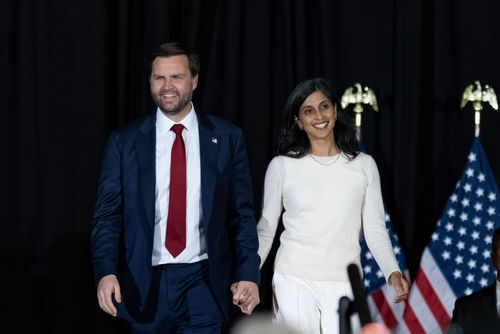 Man and woman holding hands on stage with flags