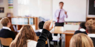 Classroom with student raising hand teacher speaking front