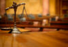 A close-up of a decorative scales of justice on a wooden table in a courtroom