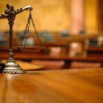 A close-up of a decorative scales of justice on a wooden table in a courtroom