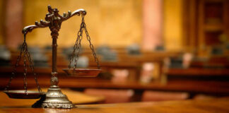 A close-up of a decorative scales of justice on a wooden table in a courtroom