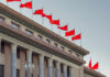 Facade of a government building adorned with red flags