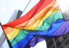 A vibrant rainbow flag waving against a city backdrop