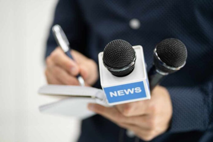 A journalist holding a notebook and microphones labeled 'NEWS'