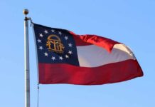 Georgia’s Red District Resists Blue Wave Georgia state flag waving against a clear blue sky