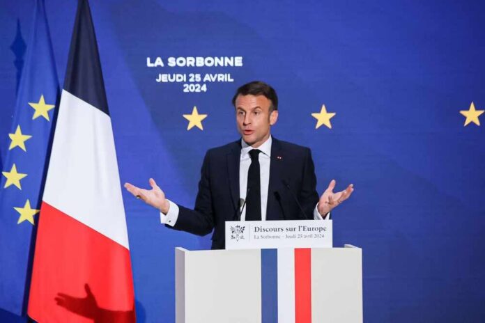 Emmanuel Macron delivering a speech at La Sorbonne with flags in the background