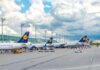 Several Lufthansa airplanes parked at an airport under a cloudy sky