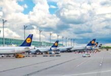 Several Lufthansa airplanes parked at an airport under a cloudy sky
