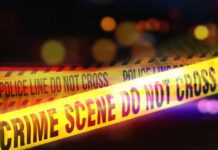 Yellow police tape marking a crime scene with blurred lights in the background