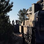 Silhouette of soldiers near a military vehicle in a wooded area