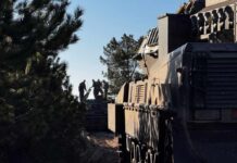 Silhouette of soldiers near a military vehicle in a wooded area